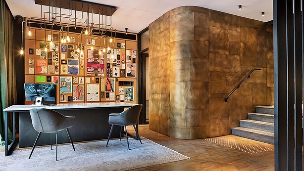 Un interior moderno con una pared curva, una zona de bar con una lámpara y una escalera.