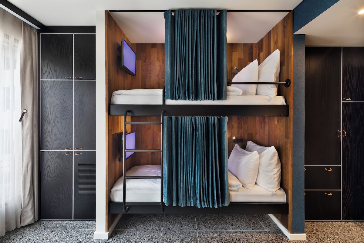 Een slaapkamer met een stapelbed, een houten wand, een televisie en een kledingkast.