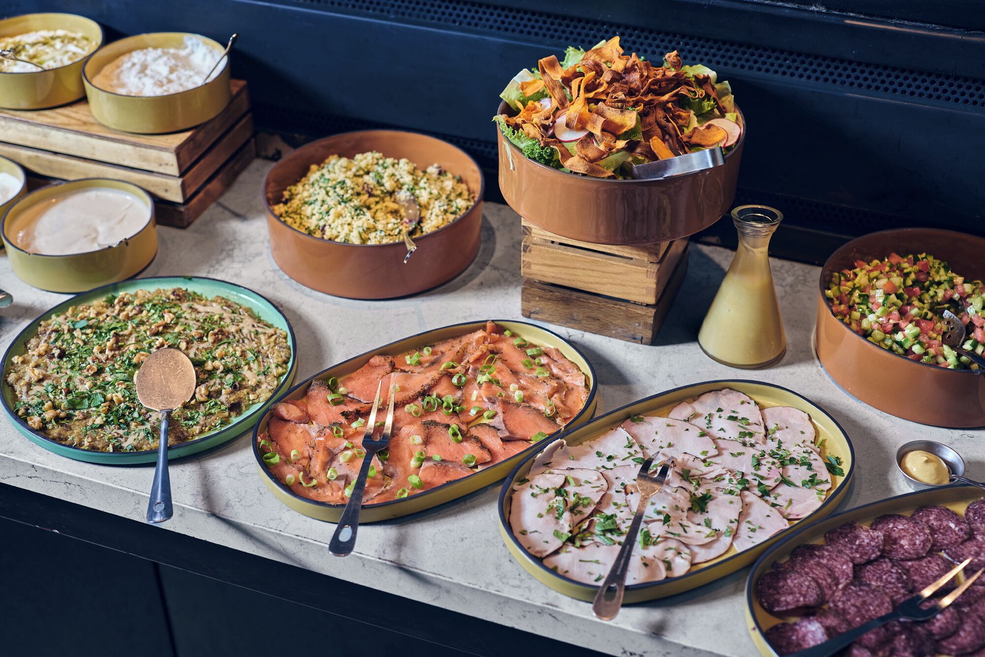 Un buffet proposant une variété de plats, notamment des salades, des viandes et un assortiment de crudités.