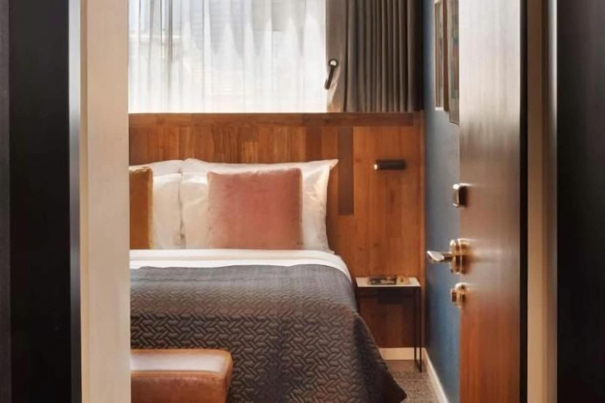 A hotel room with a bed, bedside table, and a wooden headboard.