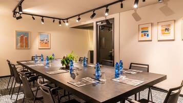 A conference room with a long table, chairs, water bottles, and framed pictures on the walls.