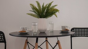 A round table with a potted fern, two cups with "HOME Sweet Home" text, a glass of water, and a plate with a pastry. - Letta's Apartments (Syros)
