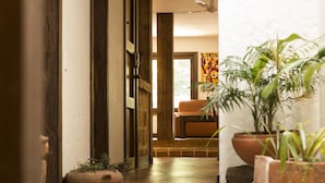 An interior view of a room with a wooden floor, a sofa, and potted plants. - Casa Del Reloj (Medellín)