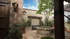 A courtyard with a brick wall, a wooden door, a bench, and potted plants. - Casa Del Reloj (Medellín)