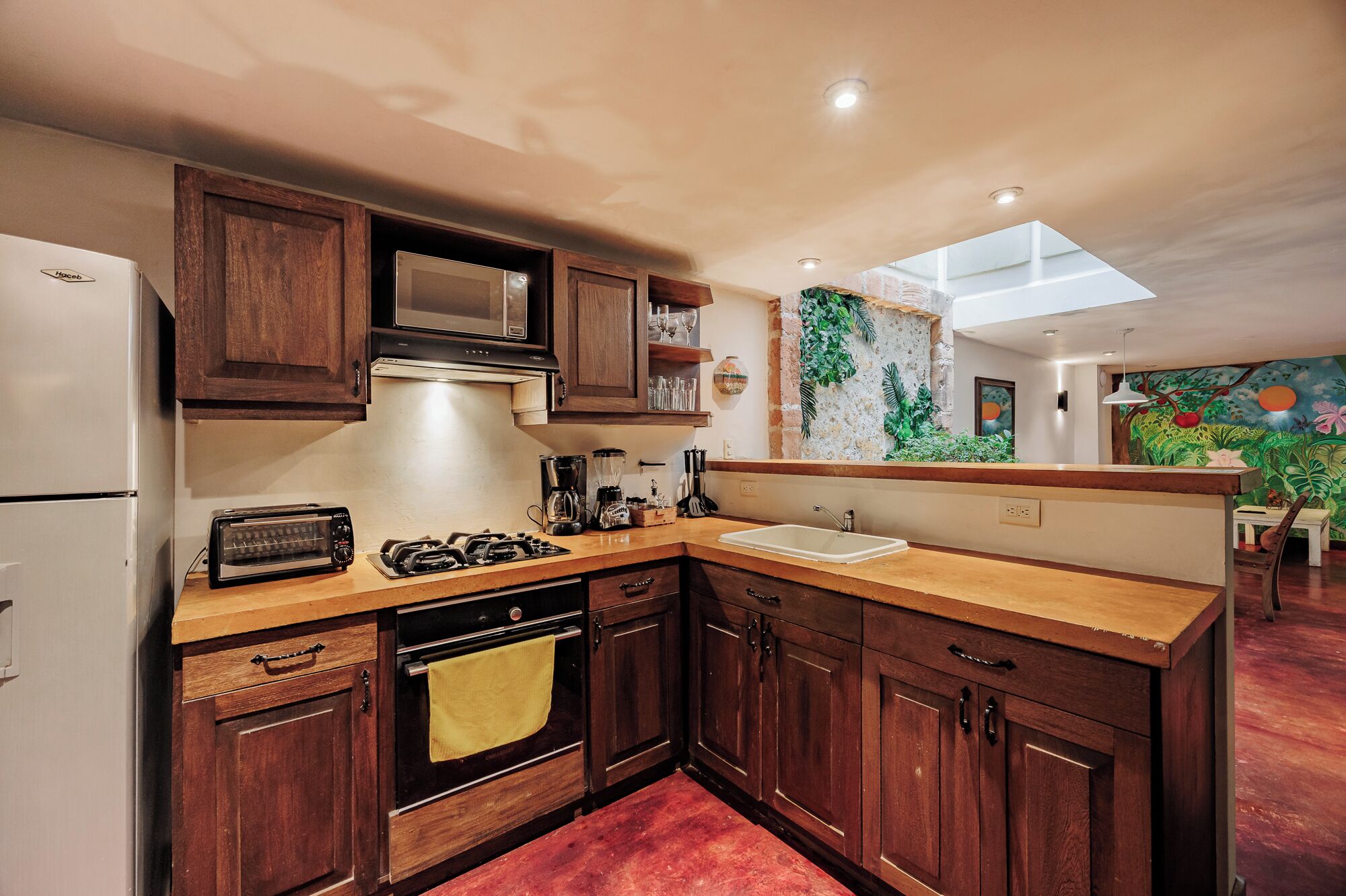 Una cocina con armarios de madera, microondas, estufa a gas y un lavabo.