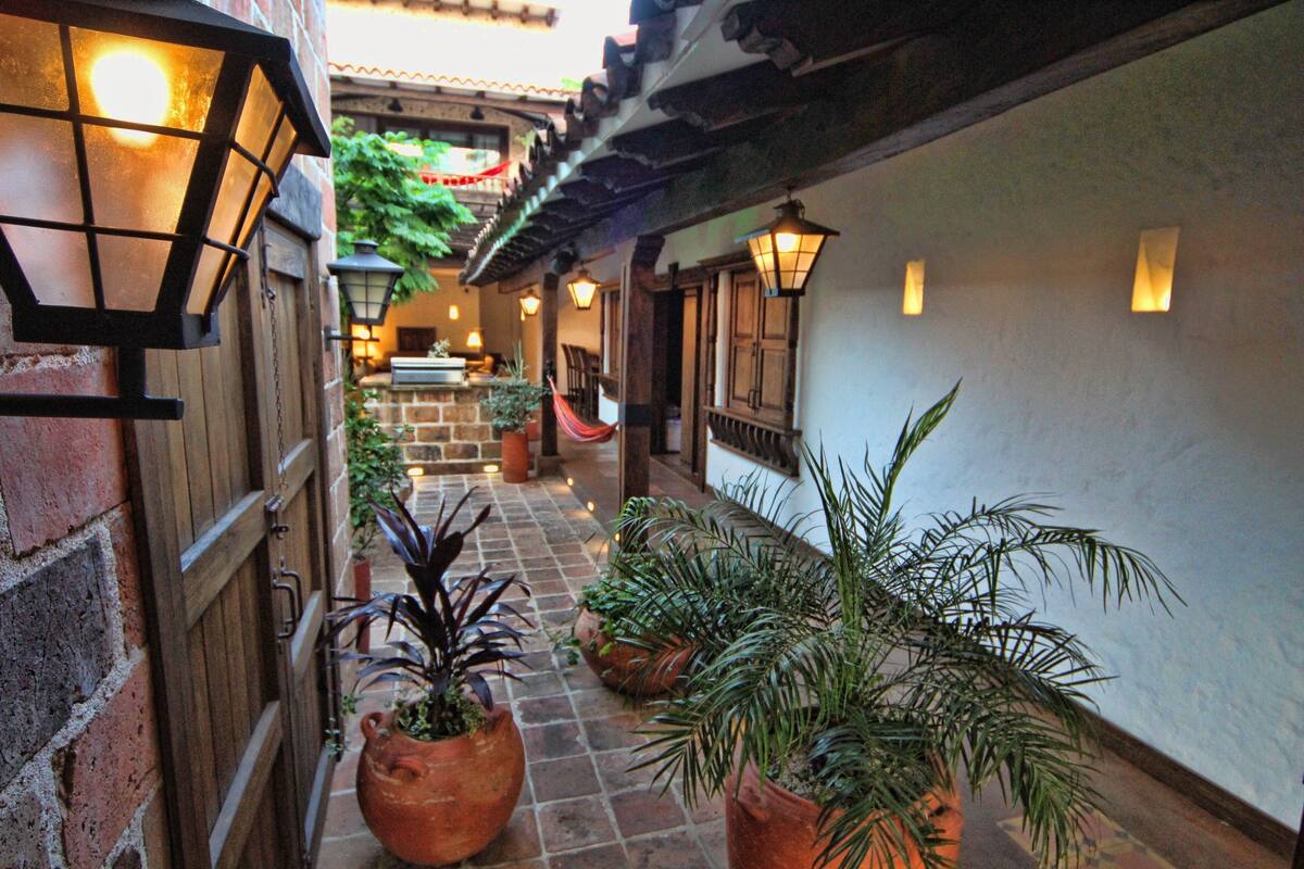A narrow alleyway with terracotta tiles, potted plants, and traditional lanterns.