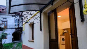 Une entrée d’immeuble avec un auvent en métal, une porte et un espace visible pour le linge.
