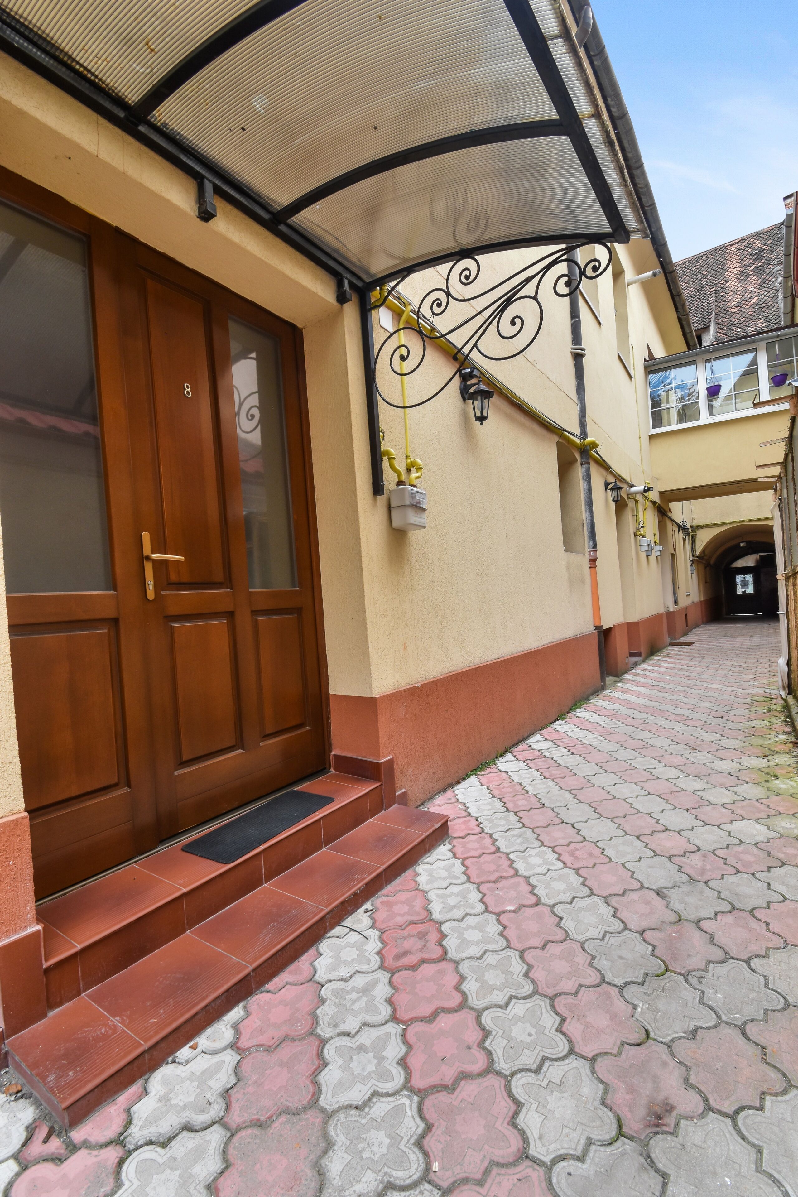 A building with a wooden door, a covered entrance, and a tiled pathway.