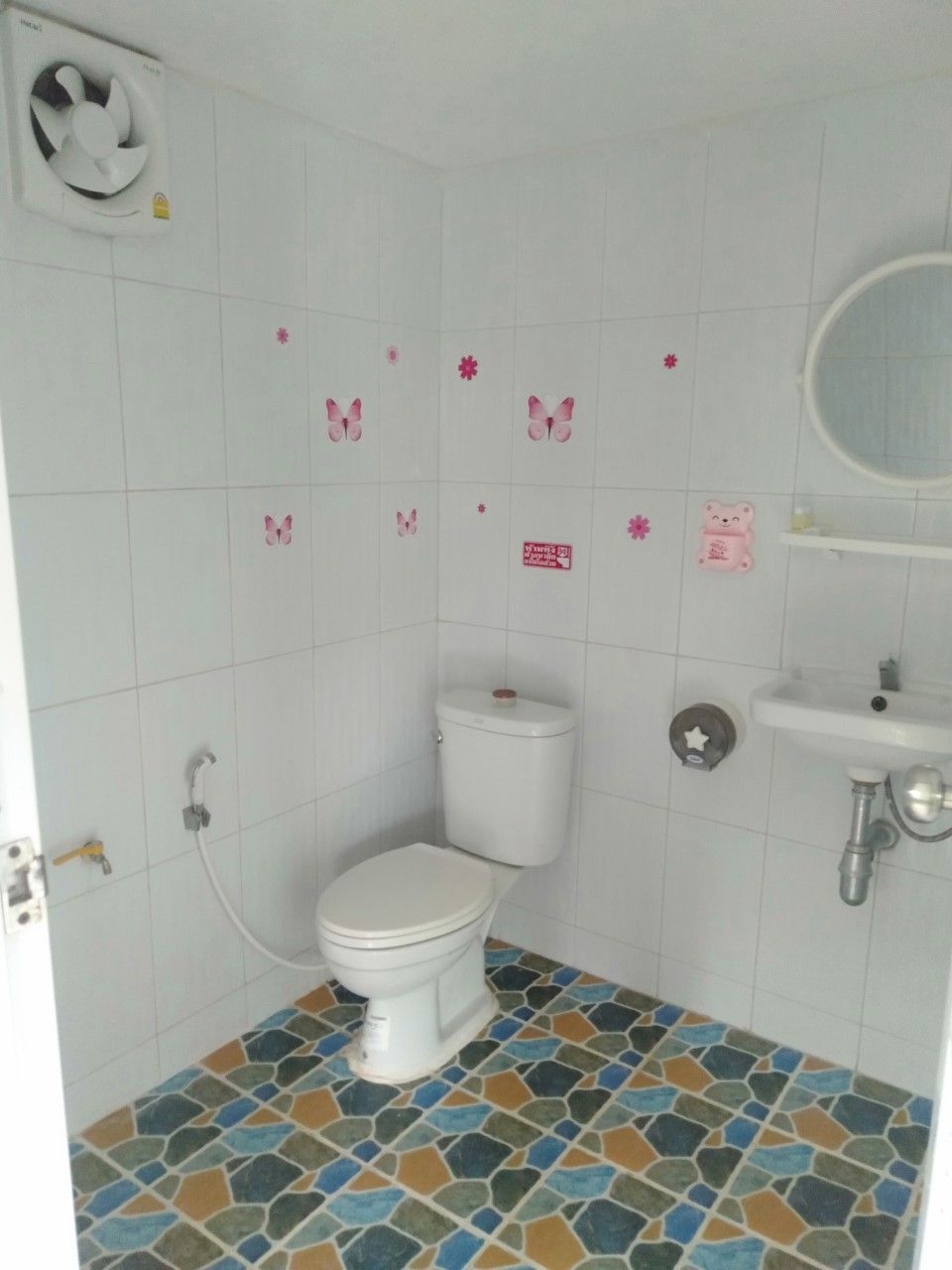 A bathroom with a toilet, sink, and decorative butterfly stickers on the wall.