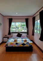Un dormitorio con una cama grande, una mesita de noche, una ventana con cortinas y vistas al exterior.