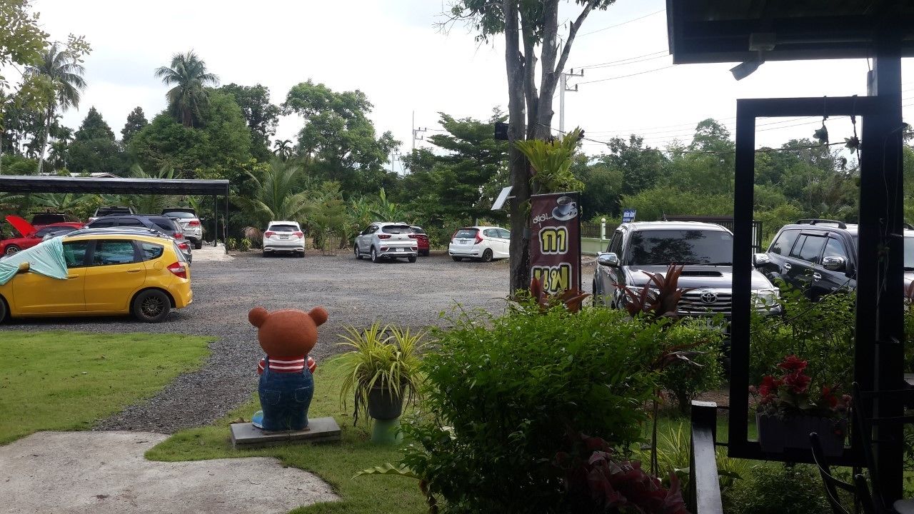 A parking area with cars, a bear statue, and greenery.