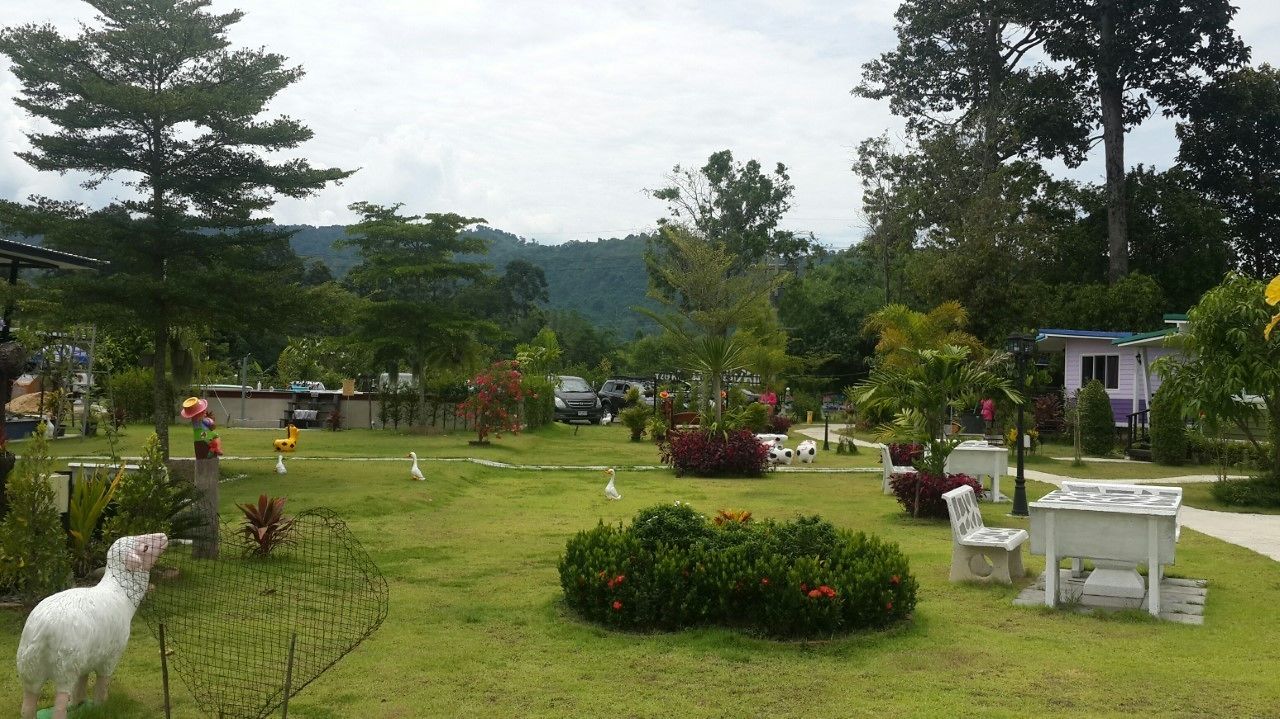 A well-maintained garden with a fenced area, a white dog statue, and a small building with a green roof.