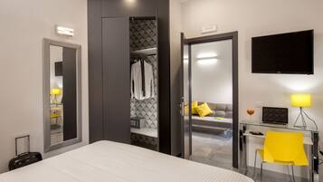 A modern hotel room with a large bed, a walk-in closet, a desk with a laptop, and a TV on the wall.