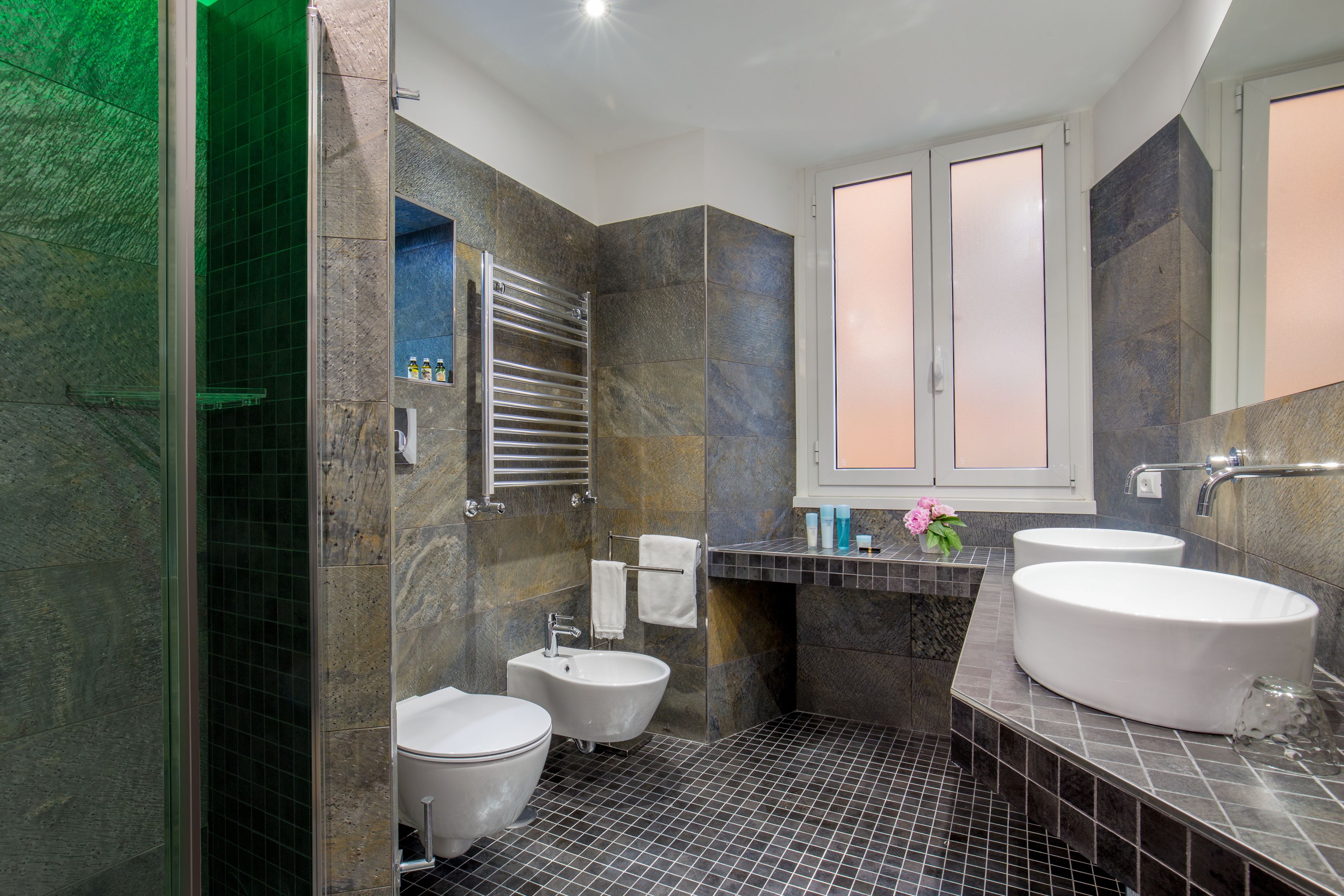 Une salle de bain moderne équipée d’une douche, de deux lavabos, de toilettes et d’un porte-serviettes.