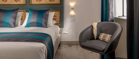Una habitación de hotel con una cama, una silla, una mesita de noche y una lámpara fijada a la pared.