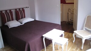 Une chambre avec un grand lit, une petite table blanche et une chaise blanche.