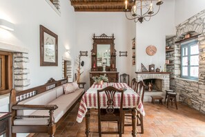 A cozy dining area with a stone fireplace, wooden furniture, and a red and white checkered tablecloth.