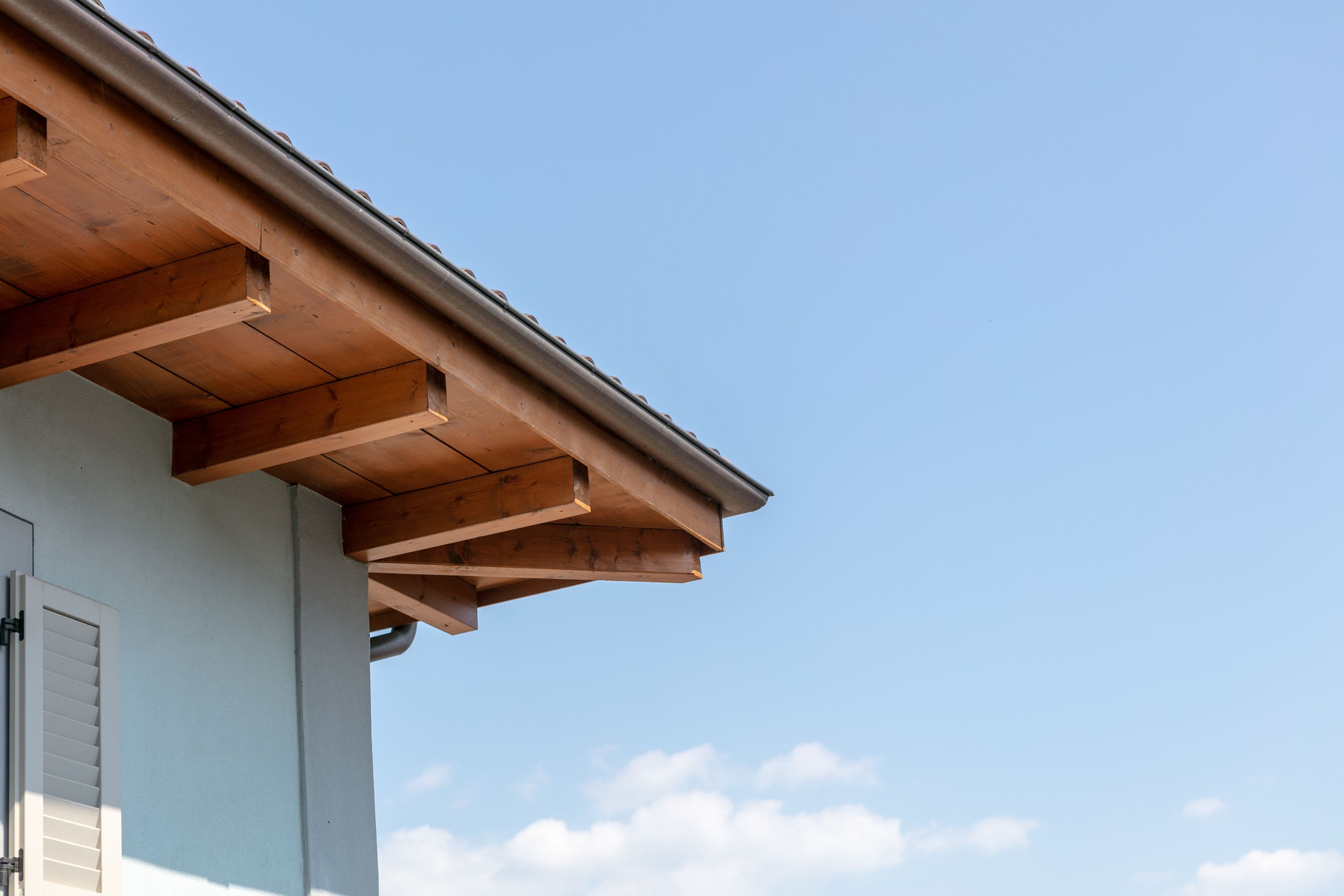 A building's roof structure with visible wooden beams and a metal gutter.