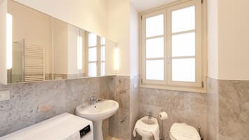 A modern bathroom with a built-in washing machine, a sink, and a toilet.