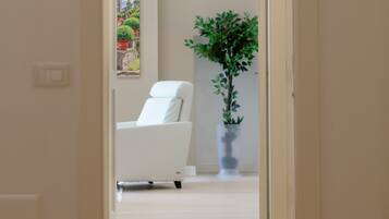 Un pasillo que conduce a un dormitorio con una cama, una silla y una planta en maceta.