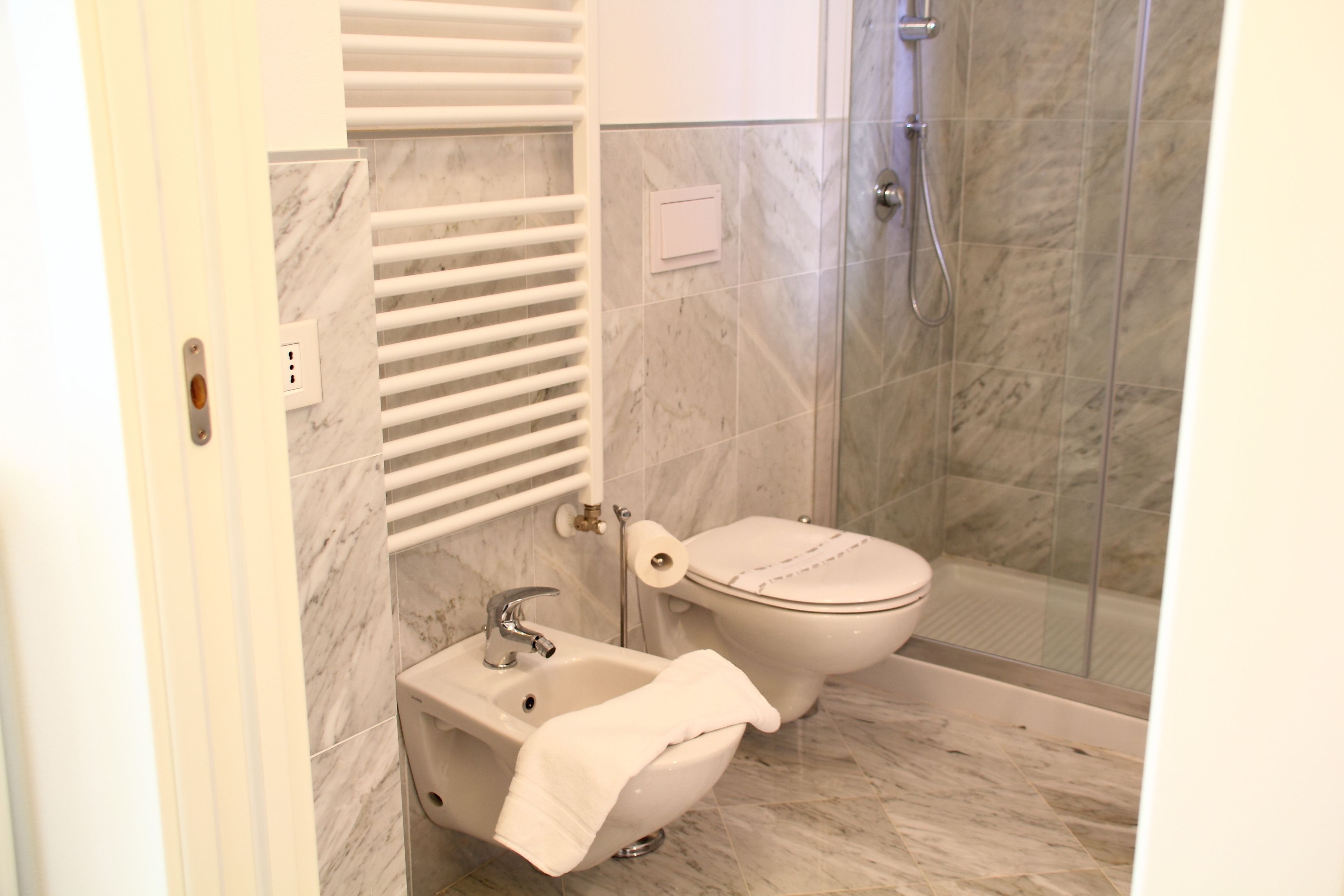 Et moderne badeværelse med bidét, toilet og bruseniche.