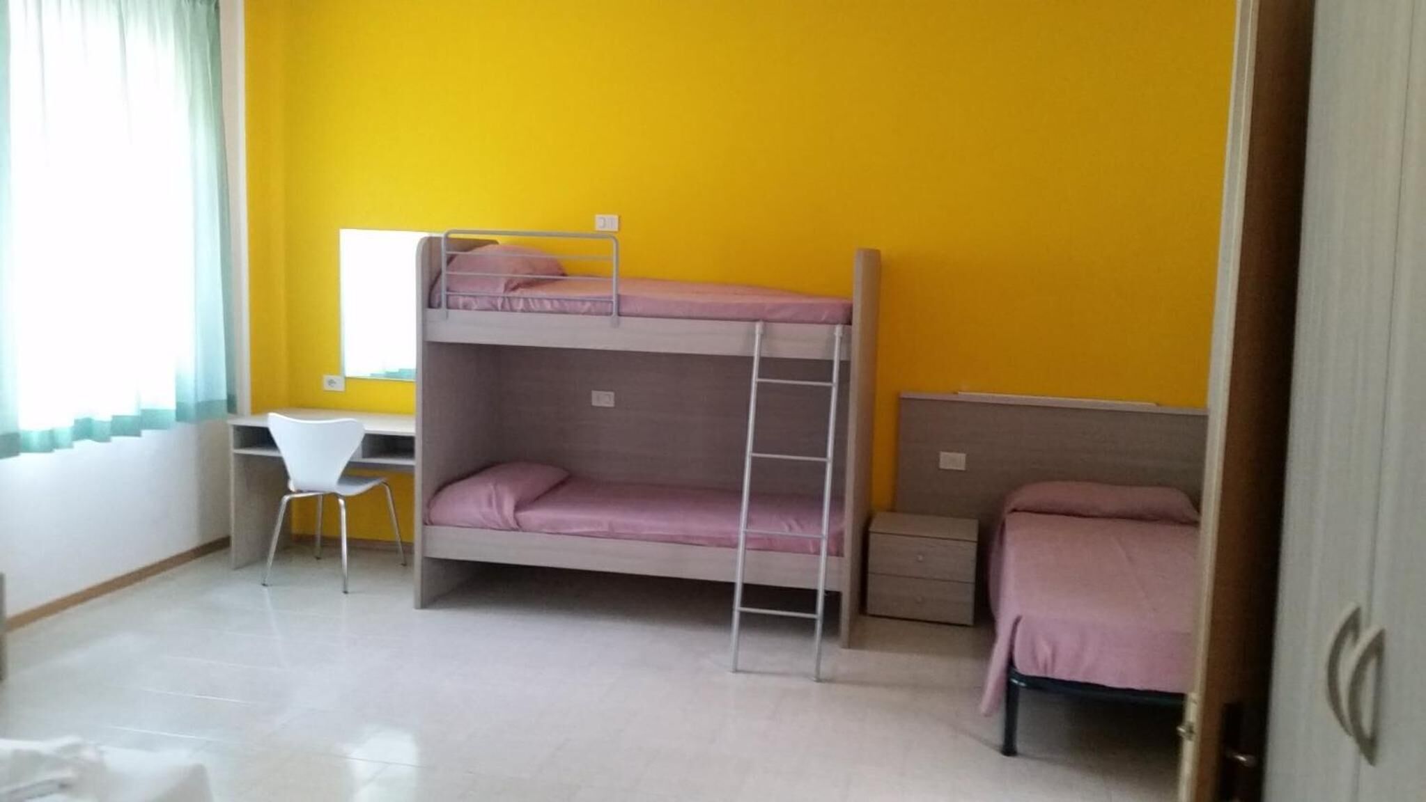 A room with a bunk bed, a desk, and a chair.
