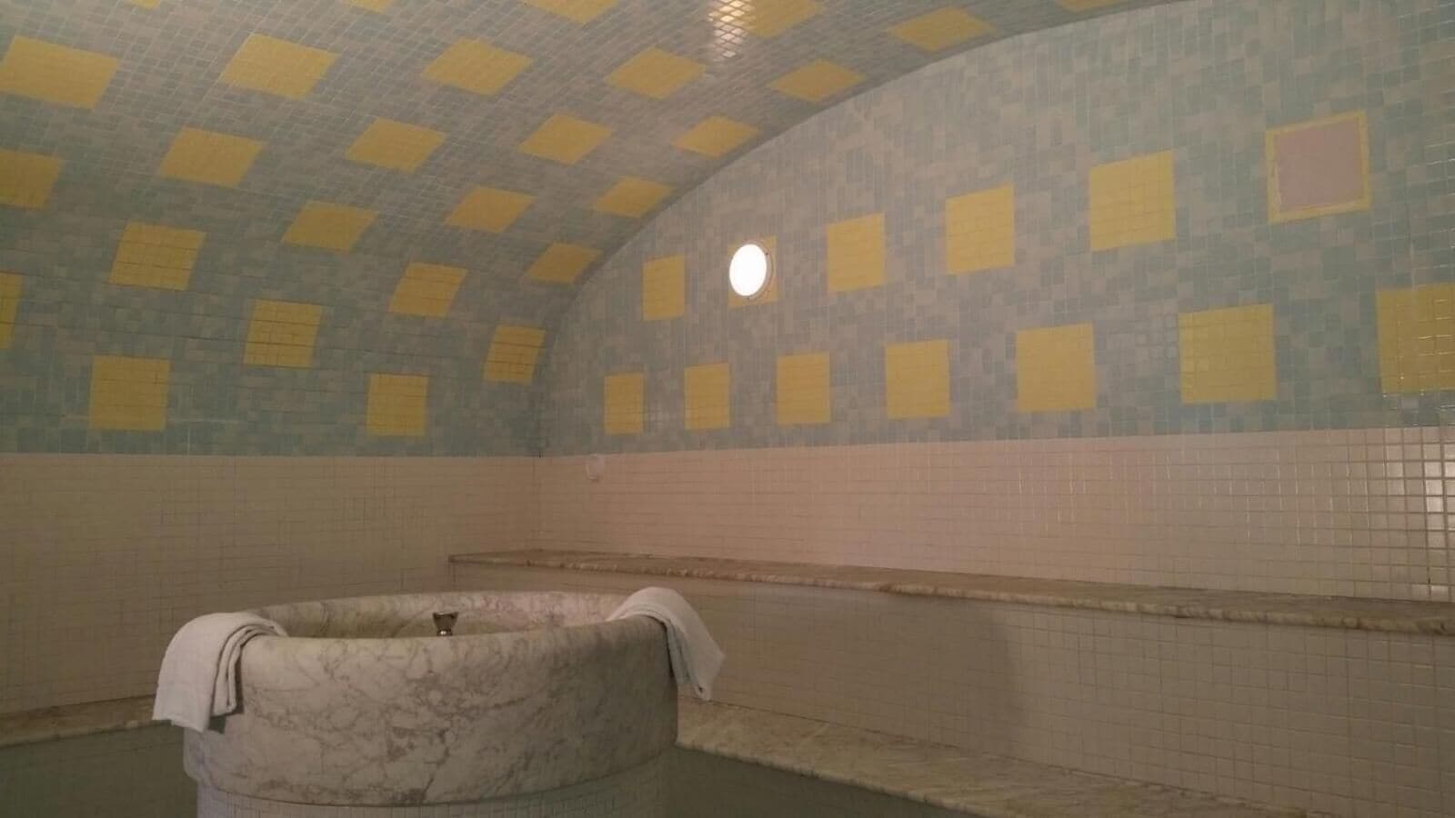 Ein gefliestes Badezimmer mit Badewanne, Duschbereich und kleinem Fenster.