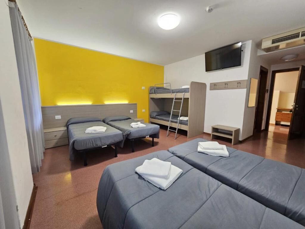 Habitación de hotel con dos camas, televisión y una cama litera.