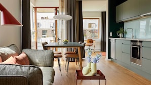 A modern living room with a sofa, a dining table, and a kitchen area with cabinets and appliances. - Charlottehaven (Copenhagen)