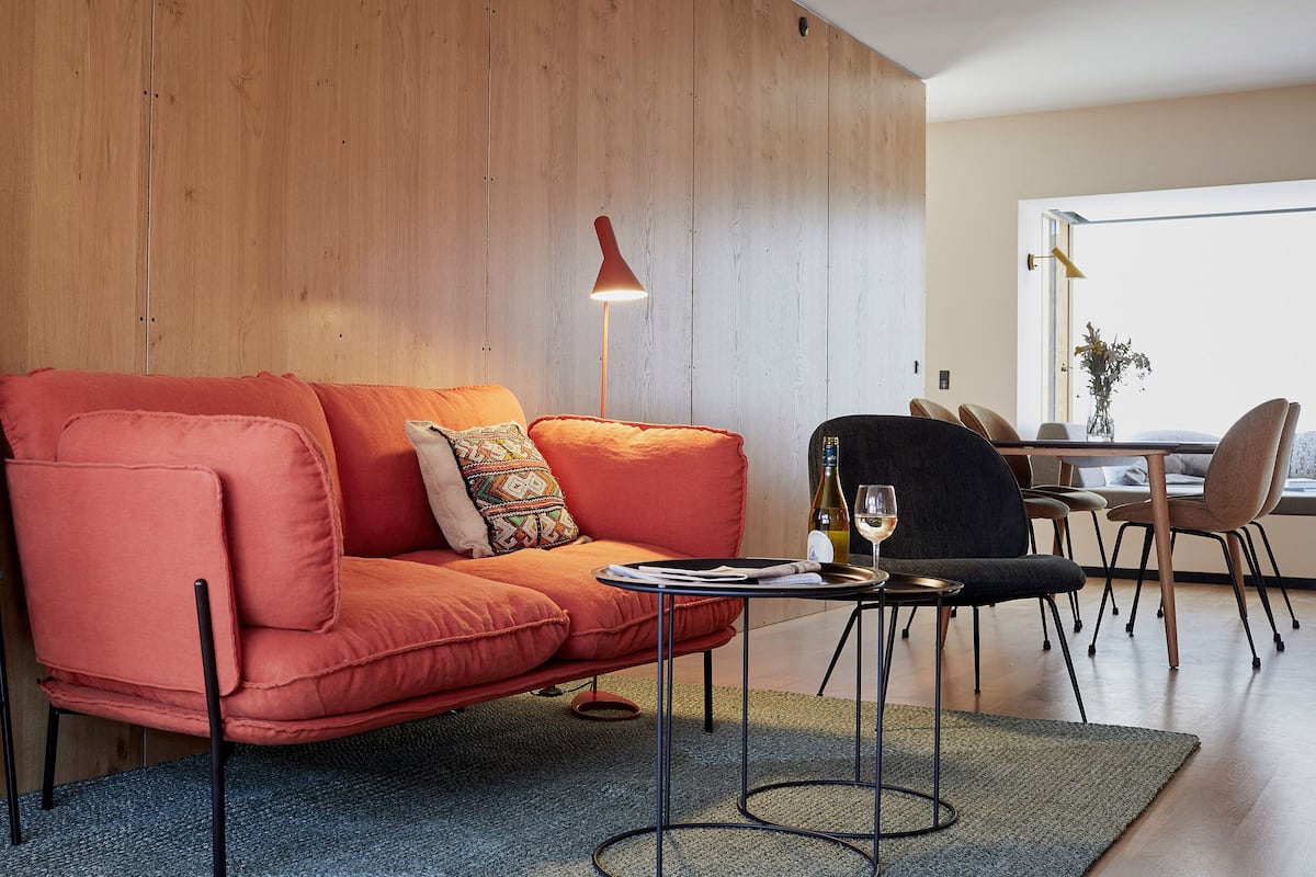 A modern living room with a sofa, a coffee table, and a dining area.