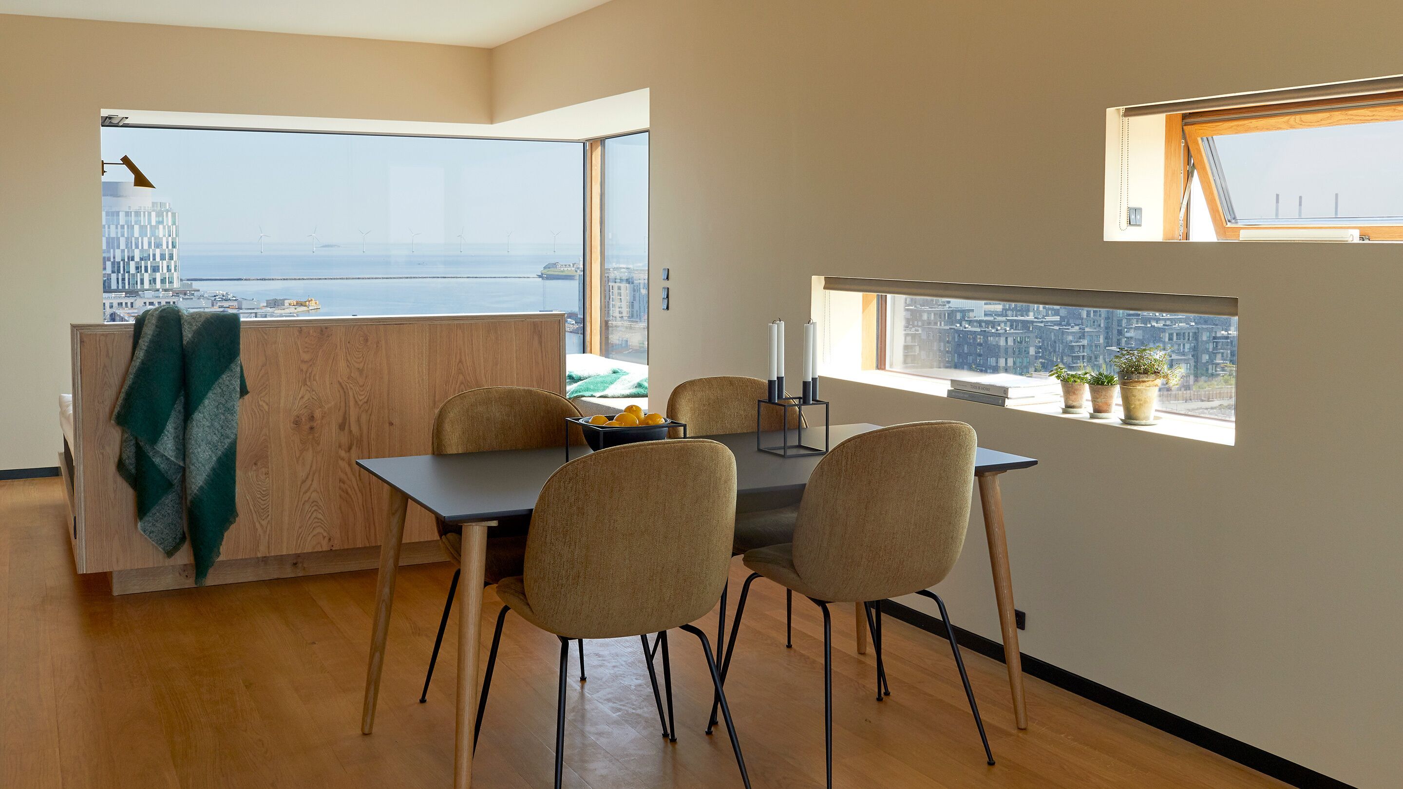 A modern dining area with a view of the city and wind turbines.