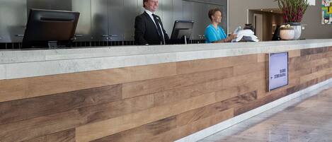 A reception desk with a modern design, featuring a wooden panel wall and a digital screen.
