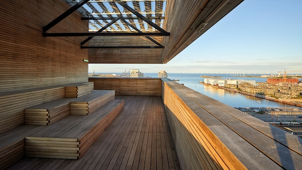 A wooden deck with built-in seating and a view of a marina and cityscape. - Charlottehaven (Copenhagen)