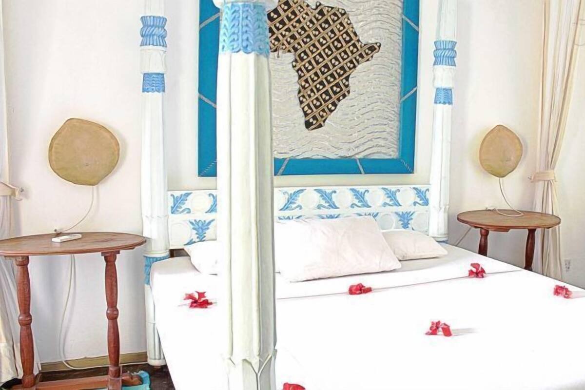 Une chambre d’hôtel comprenant un lit, deux tables de chevet, une horloge murale et un élément décoratif fixé au mur.