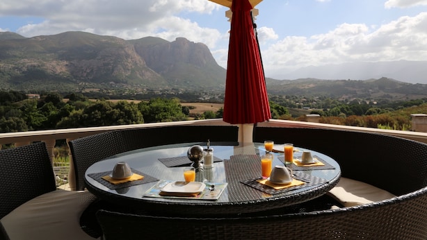 Mesa de comedor con vista a las montañas y un paraguas rojo.