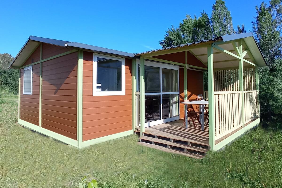 Uma pequena cabana de madeira com varanda e mesa.