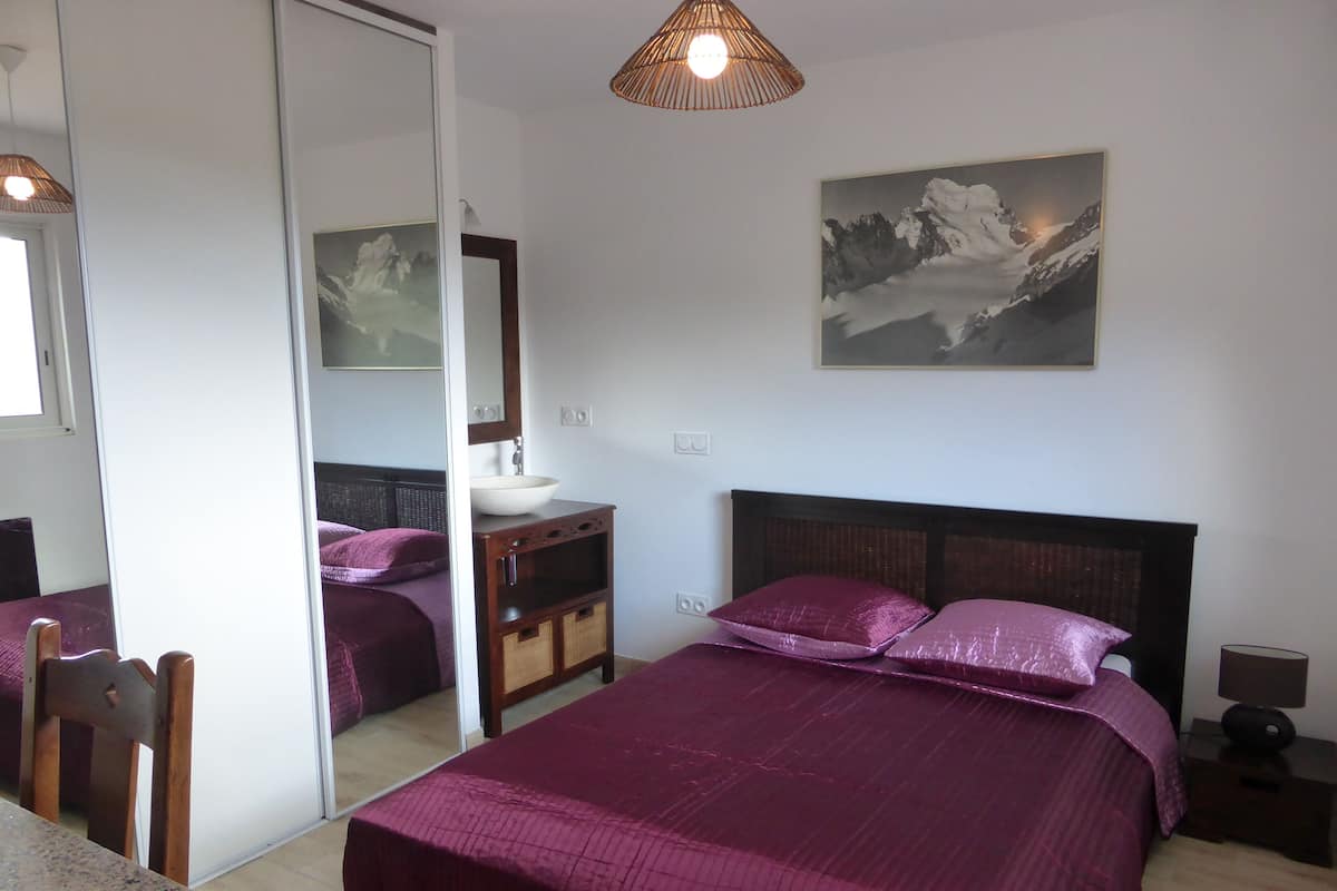 Um quarto com uma cama grande, uma mesa de cabeceira, um espelho e um quadro na parede.