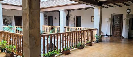 A covered wooden deck with potted plants, a wooden railing, and a stone pillar.