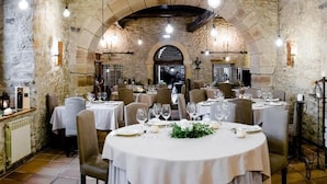 Een restaurant met stenen muren, ronde tafels en stoelen.
