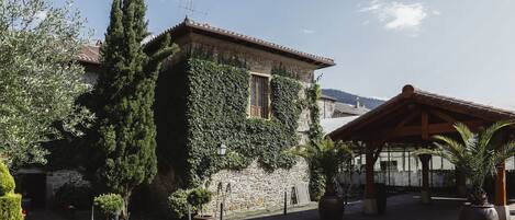 A courtyard with stone buildings, potted plants, and a wooden pergola.