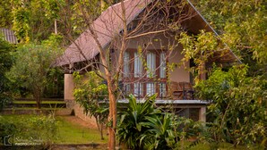 A house with a sloped roof, surrounded by lush greenery and a small pond. - Hantara Udawalawa (Udawalawa)