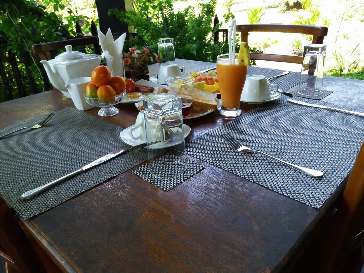 A wooden table set with breakfast items including toast, fruit, and a glass of orange juice.