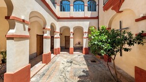 A courtyard with arches, a tiled floor, and a balcony with railings. - Palacio Bucarelli (Seville)