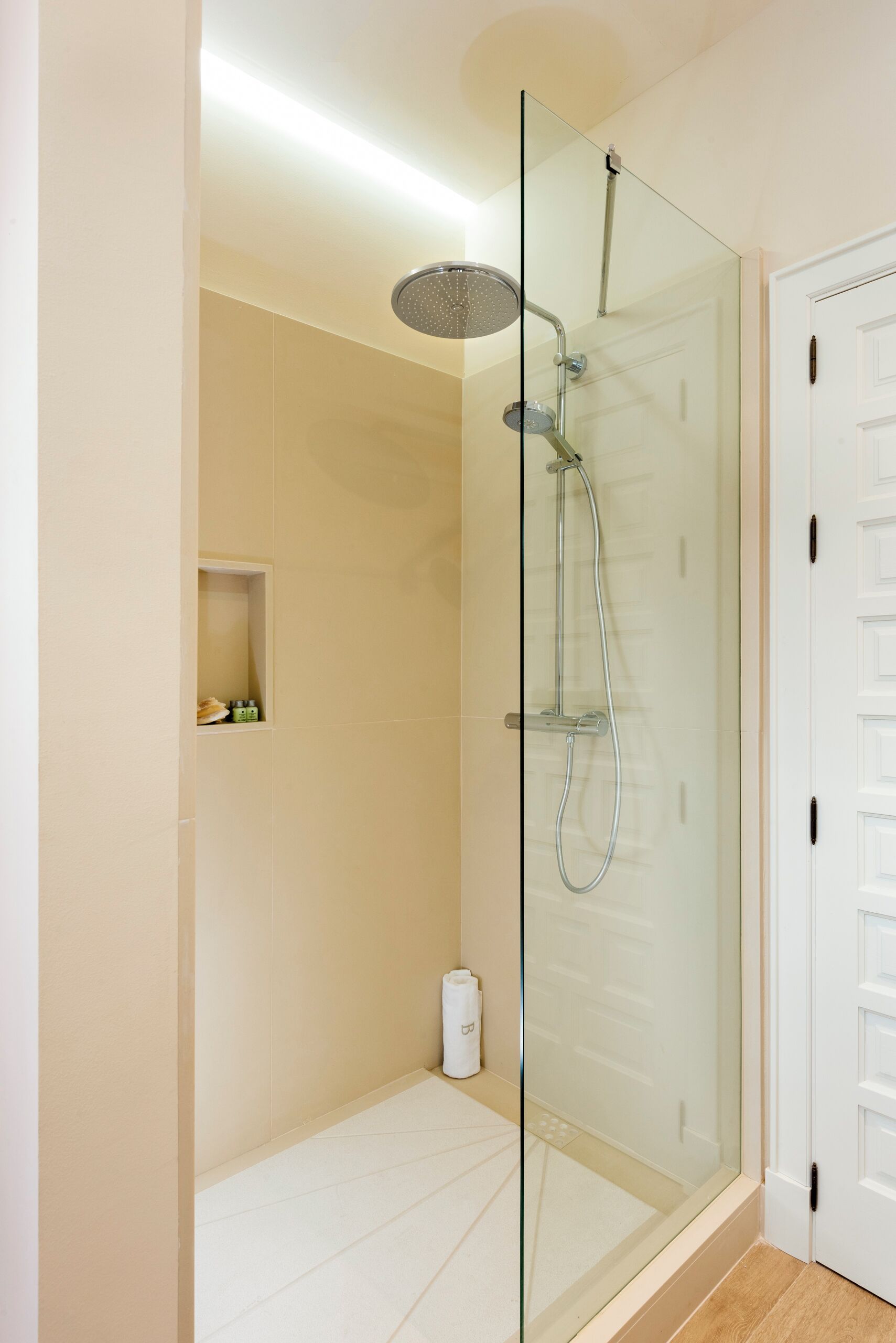 A glass-enclosed shower stall with a handheld showerhead and a wall-mounted faucet.