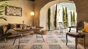 A cozy interior with a rustic stone wall, a wooden table with candles, and a patterned floor. - Palacio Bucarelli (Seville)