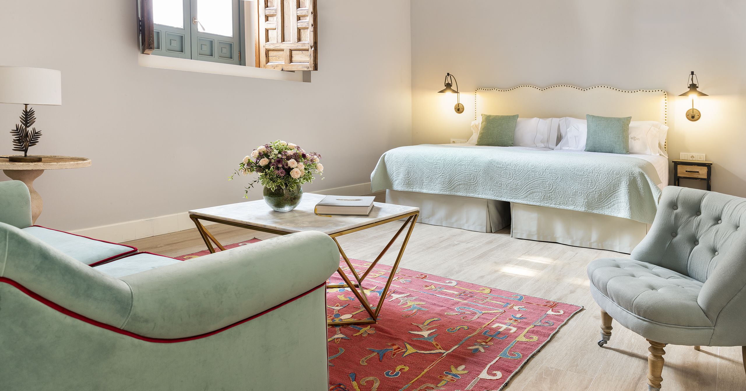 Une chambre à coucher avec un lit, des tables de chevet, une lampe, une chaise, une table et un tapis.