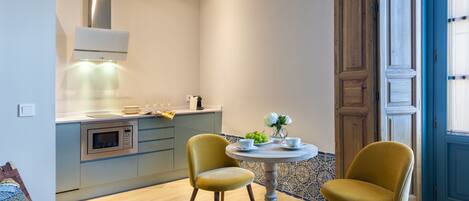 A modern kitchen with a built-in microwave, a wooden bench, and a dining table with two chairs.