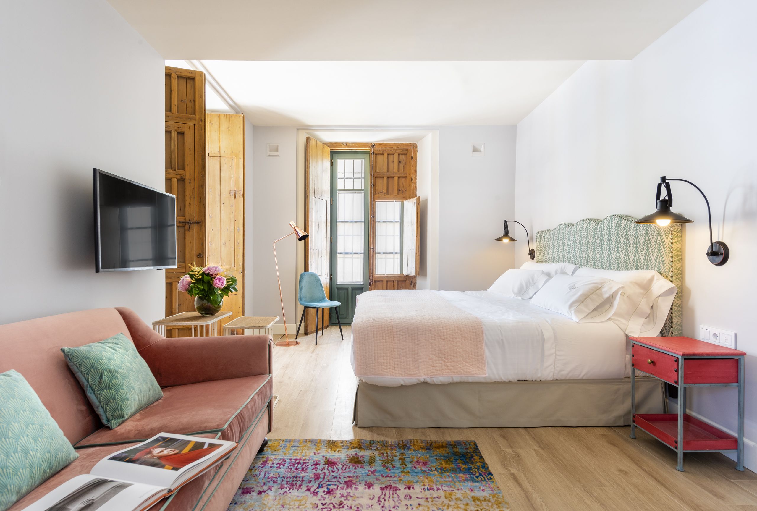 Un dormitorio con una cama, televisión, escritorio y silla.