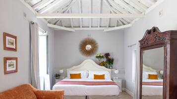 A bedroom with a large bed, a wooden wardrobe, a sofa, and a mirror.