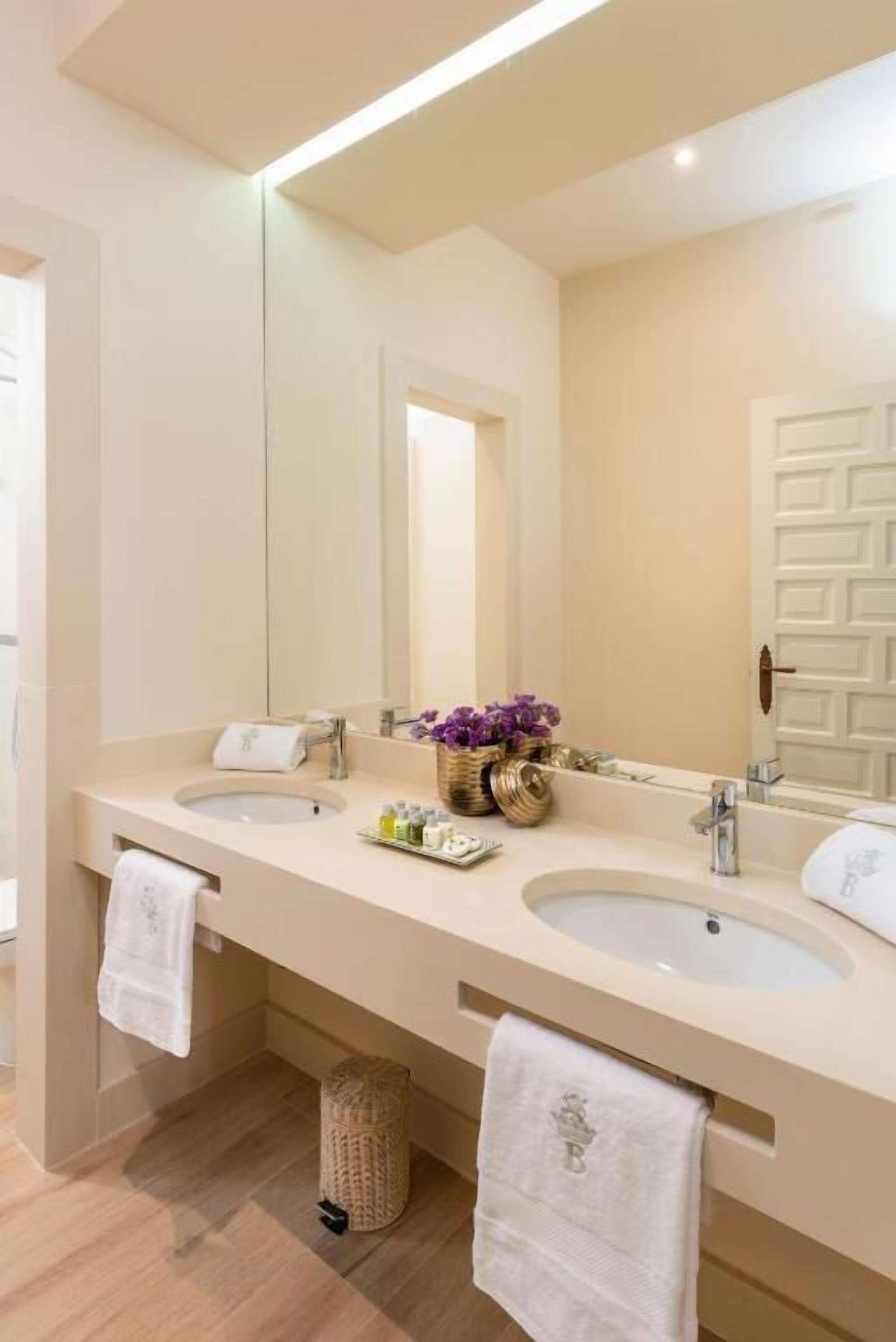 A modern bathroom with two sinks, a large mirror, and a towel rack.